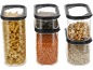 Three clear food containers with black lids, filled with pasta, lentils, nuts, and oats.