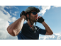 Man in a cycling helmet, sunglasses, and gloves against a sky background.