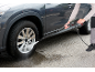 Man cleaning a dirty car wheel with a pressure washer.