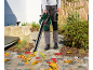 Person using a leaf blower to clear autumn leaves from a paved path.