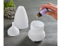 Female hand adding lavender essential oil to a white diffuser, next to a lavender bouquet.