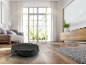 Robot vacuum cleaner cleaning a wooden floor in a bright living room.