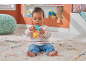 Baby sitting on a rug, playing with a colorful rattle.