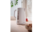 White electric kettle on a wooden countertop with a cup of tea and cookies.