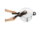 Hands operating a white pressure cooker with black and orange handles.