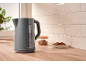 Grey kettle with cookies and a glass jar in a modern kitchen.