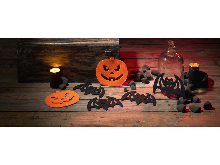 Halloween decorations with pumpkins, bats, candles, and a bottle on a wooden table.