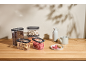 Clear food storage containers with coffee beans, nuts, and dried fruit on a wooden counter.