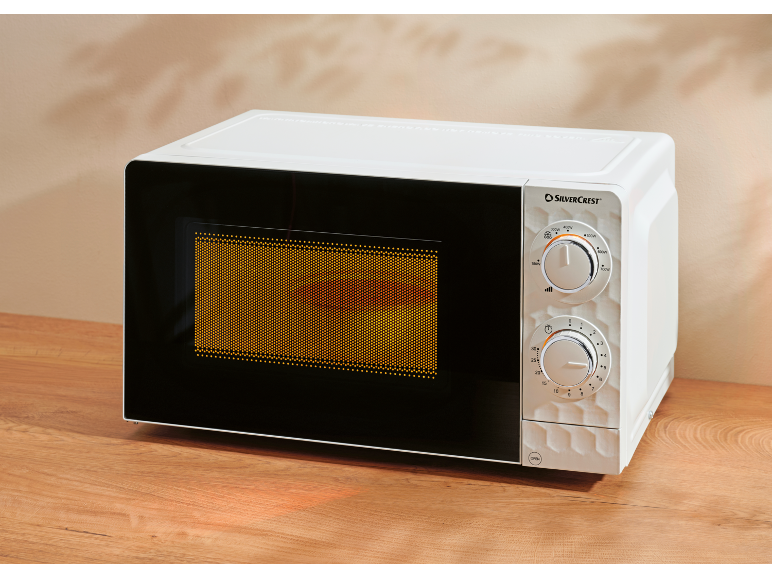 White microwave with control panel and black door on a wooden table.