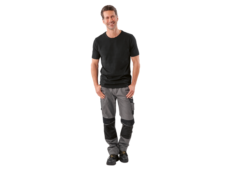 Smiling man in black t-shirt and grey and black work trousers.