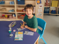 Smiling boy writing in a cat-shaped notebook, with cat-themed school supplies.