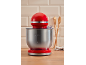 Red stand mixer with a stainless steel bowl in a modern kitchen setting.