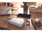 White TRONIC power bank charging a smartphone and laptop on a wooden table.