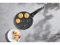 Pancake pan with pancakes and a plate of pancakes with fruit and chocolate.