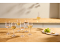Wine glasses with white wine and a carafe on a wooden counter, with grapes and crackers.
