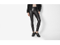 Woman in black faux leather leggings, black jacket, and buckled loafers.