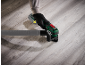 Cordless multi-tool with dust extraction attachment on a wooden floor.