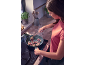Woman cooking sage and prosciutto meat on an induction hob.