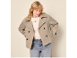 Woman in a beige short coat, cream sweater, and jeans.
