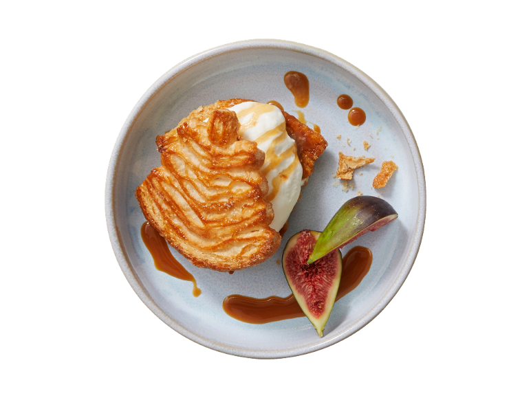 Puff pastry dessert with ice cream, caramel sauce, and fresh figs on a plate.