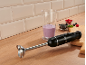 Black immersion blender with berry smoothie and fruits on a wooden countertop.