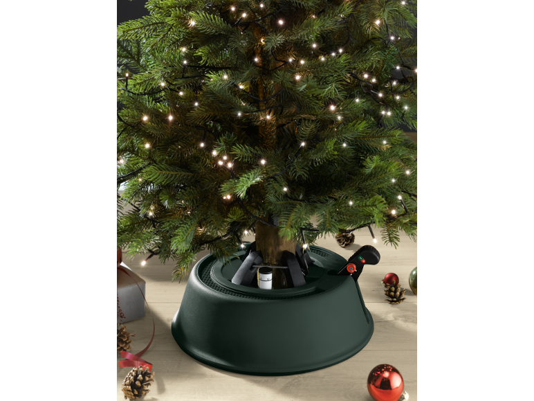 Lit Christmas tree with a green stand and festive decorations.