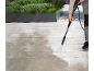 Person cleaning a patio with a pressure washer, showing before and after results.