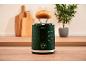 Green toaster with a bun on top, in a kitchen with cutting boards.
