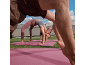 People in sportswear doing yoga on pink mats on grass.