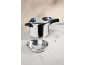 Stainless steel pressure cooker with steamer basket and trivet on a white marble surface.