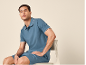 Man in blue polo shirt and shorts sitting on a chair.