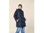 Smiling woman in a navy blue hooded raincoat and jeans.