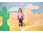 Smiling girl in a pink and purple hooded jacket and purple sweatpants with a unicorn print.