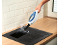 Handheld steam cleaner cleaning a hob on a wooden countertop.
