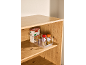 Clear organizer with penne pasta and two spice jars on a wooden shelf.