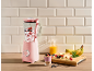 Pink blender with berries and yogurt, with fresh fruit and juice in a kitchen.