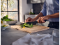 Person chopping vegetables on a wooden cutting board in a kitchen.