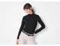 Smiling woman in black ribbed high-neck top and beige trousers.
