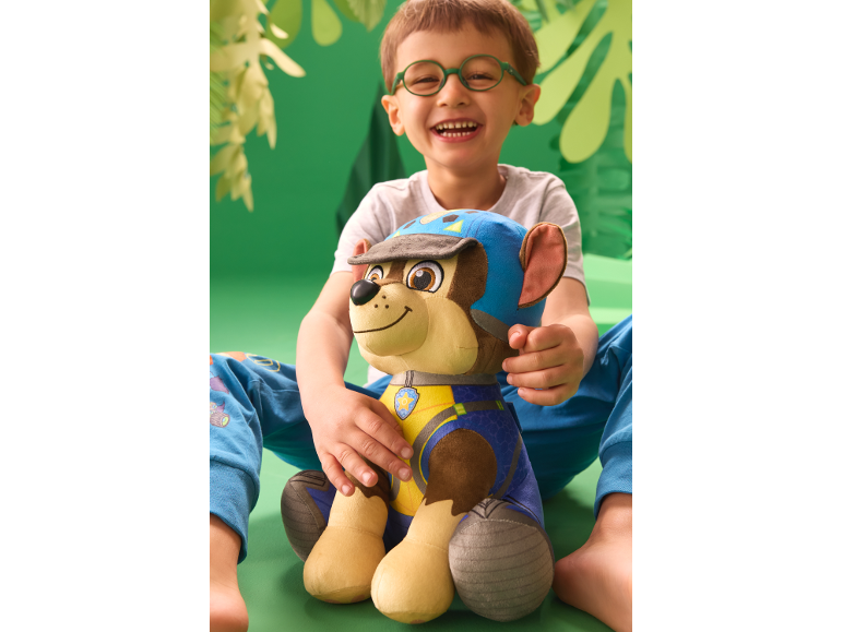 Smiling boy with glasses and a plush dog on a green background.