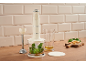 Cream hand blender with accessories, herbs, oil, and cheese on a wooden countertop.