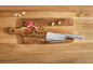 Meat cleaver with lamb chop, garlic, and rosemary on a wooden board.