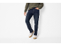 Man in dark green sweater and dark blue jeans, white and brown sneakers.
