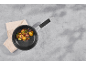 Frying pan with fried potatoes and bacon on a grey table with a napkin.