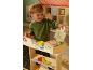 Child playing with a toy cash register and pretend food, including meat, cheese, and fish.