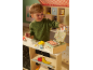 Child playing with wooden toys, including a cash register and food items.