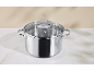 Stainless steel cooking pot with a glass lid on a white marble surface.