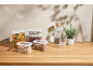 Food storage containers with pasta, cereals, and legumes on a wooden table.