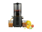 Black slow juicer with fruit and juice in a glass.