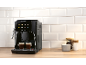 Black automatic coffee machine with two espresso cups and jars of coffee and sugar.