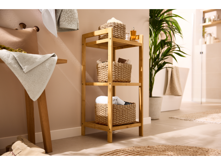 Bamboo bathroom shelf with woven baskets, towels, and a plant.